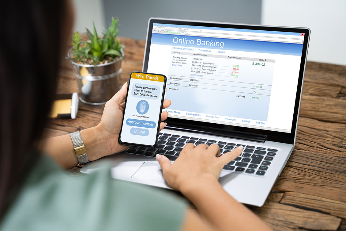 Woman Using Mobile Phone App To Authenthificate Bank Transfer On Laptop in stead of Google Authonticator